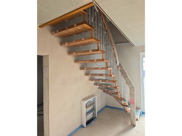Eingebaute, moderne Holztreppe im Flur des schlüsselfertigen Massivhauses während der Ausbauphase.