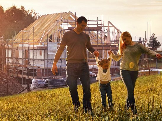 Familie vor dem Rohbau ihres Hauses
