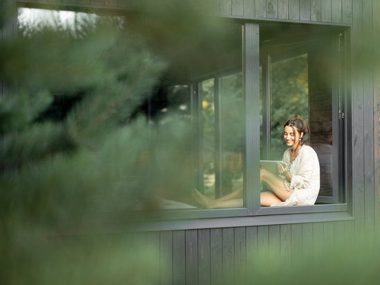 Frau sitzt am Fenster in ihrem neuen Haus