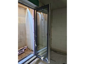 Nahaufnahme eines geöffneten, dreifach verglasten Fensters direkt nach der Montage im Massivhaus.