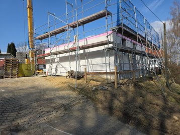 Das gemauerte Erdgeschoss im Rohbau des schlüsselfertigen Massivhauses mit Baugerüst in Niederaichbach.
