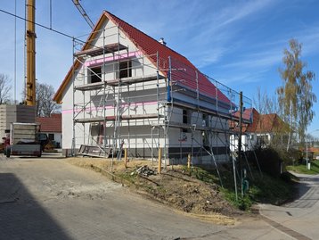 Außenansicht des Massivhaus-Rohbaus vom Typ Flair 110 in Niederaichbach mit fertig aufgestelltem Dachstuhl vor dem Fenstereinbau.