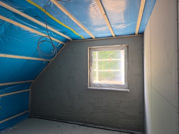 Isolierung und blaue Dampfbremsfolie an der Dachschräge beim Innenausbau des Hauses in Niederaichbach.