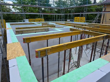 Blick auf die gemauerten Wände des Erdgeschosses und die vorbereitete Holzschalung für die Zwischendecke.
