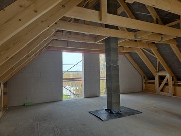Blick in den offenen, frisch aufgestellten Holzdachstuhl des Massivhauses Flair 152 RE von innen.