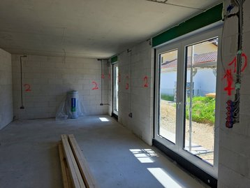 Große, moderne Fensterelemente und Terrassentüren frisch eingebaut im hellen Wohnzimmer des Flair 152 RE.