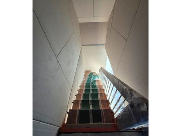 Rohbautreppe aus Holz mit Schutzfolie und grünem Teppichschoner, Blick nach oben im Neubau.